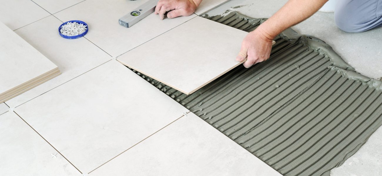 Laying Ceramic Tiles. The hands of the worker are laying the ceramic tile on the floor.